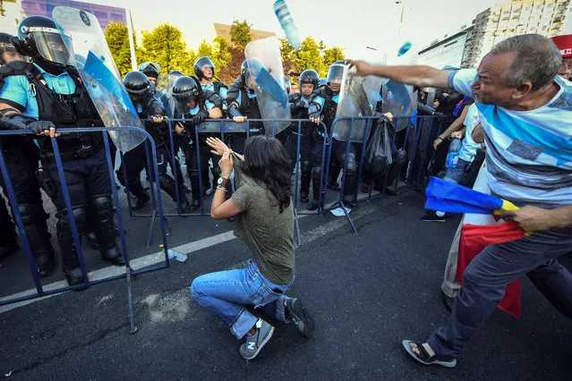 Romanian anti riot police clash with protesters throwing plastic bottles at them during a demonstration in front of the Romanian Government headquarters in Bucharest August 10, 2018, to protest against the government. Romanian police used tear gas and pepper spray to quell anti-corruption protesters in Bucharest on August 10, 2018, as tens of thousands called on the leftwing government to resign. Local media said between 30,000 to 50,000 people turned out for the protest, included many Romanian expatriates who returned home especially to show their anger at the levels of official corruption. The crowd chanted “resign” and “thieves” as they assembled in a central square outside the main government building. (Photo by Daniel Mihailescu/AFP Photo)