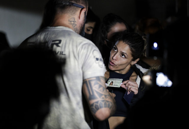 A woman presents her identification as police break up a social gathering during an operation against illegal and clandestine gatherings that authorities believe are partly responsible for fueling the spread of COVID-19, at a party hall in Sao Paulo, Brazil, early Saturday, April 17, 2021. (Photo by Marcelo Chello/AP Photo)