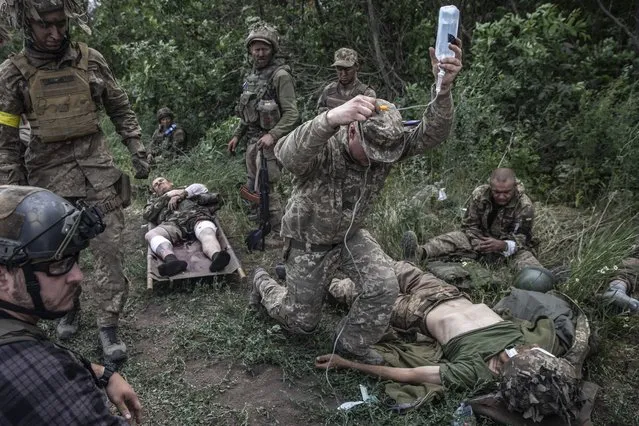 Wounded soldiers of the Ukrainian Airborne unit are treated outside the embattled city of Lysychansk, Ukraine on June 26,2022. Eight soldiers were wounded, two seriously, A Russian cluster bomb attack hit them as they moved into the farm village of Verkhniokamianske. The Ukrainian Airborne unit was relieved to be pulling away from the front Sunday morning, riding a column of armored personnel carriers away from the embattled city of Severodonetsk, which had already fallen to the Russians, and Lysychansk, which was on the brink. (Photo by Heidi Levine/The Washington Post)