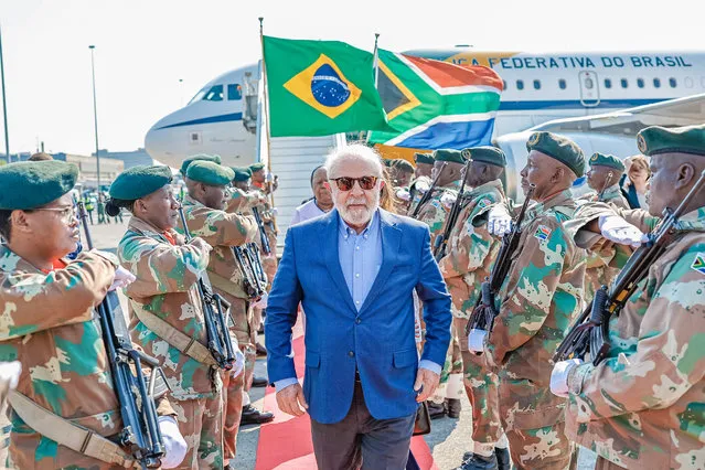 This handout photograph taken and released by the Brazilian Presidency on August 21, 2023 shows soldiers of the South African National Defence Force (SANDF) make an honour guard as President of Brazil Luiz Inacio Lula da Silva (C) arrives at the OR Tambo International Airport in Ekurhuleni, ahead of the 2023 BRICS Summit. The BRICS countries, an acronym of the five members Brazil, Russia, India, China and South Africa, meet for three days for a summit in Johannesburg starting August 22, 2023. (Photo by Ricardo STUCKERT/Brazilian Presidency via AFP Photo)