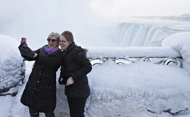 Visitors Rosalie Vissers, left, and Rachel Houter take a photo near masses of ice formed around the Canadian “Horseshoe” Falls in Niagara Falls, Ontario, Canada, Thursday, February 19, 2015. (Photo by Aaron Lynett/AP Photo/The Canadian Press)