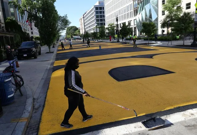 Tamika Cain, a volunteer, touches up the edges of newly painted “Black Lives Matter” along 16th Street after some road work caused the original words to be removed in downtown Washington, U.S. May 13, 2021. (Photo by Leah Millis/Reuters)