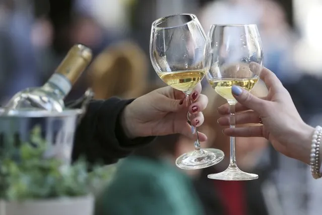 Women toast with white wine at a table in the outdoor area of a restaurant, in Duesseldorf, Germany, Friday, May 21, 2021. After months of forced break, restaurateurs in Duesseldorf are allowed to welcome guests again as of Friday. As in other municipalities in North Rhine-Westphalia, this only applies to the outdoor area and under certain coronavirus measures. (Photo by David Young/dpa via AP Photo)