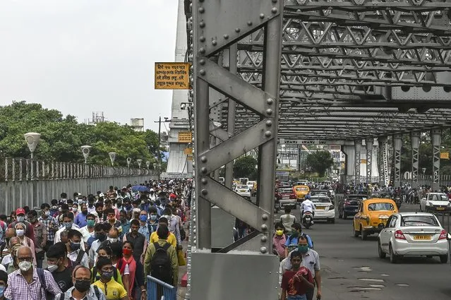 Commuters walk while crossing the Howrah Bridge as the state government suspended regular public transport during a lockdown imposed to curb the spread of the Covid-19 coronavirus, in Kolkata on June 23, 2021. (Photo by Dibyangshu Sarkar/AFP Photo)
