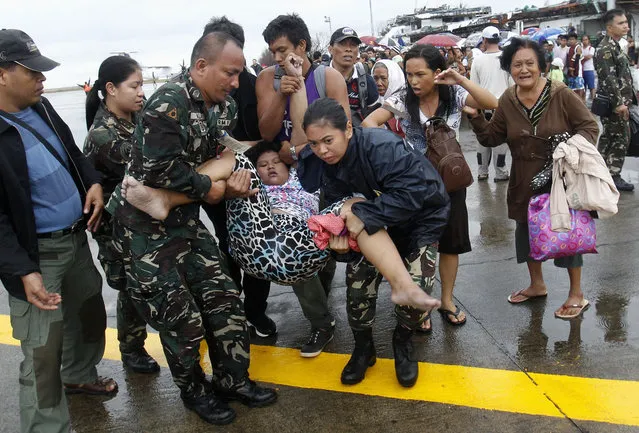 Military personnel carry a woman after she fainted while waiting in line to leave the town on military air transport, at the destroyed airport after super typhoon Haiyan battered Tacloban City, in central Philippines November 12, 2013. (Photo by Edgar Su/Reuters)