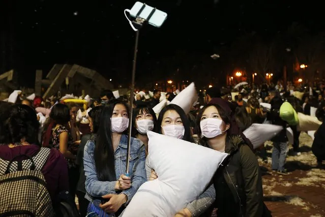 A group of bystanders wearing surgical masks take a photograph with a “selfie” stick during The Great San Francisco Valentine's Day Pillow Fight, in San Francisco February 14, 2015. (Photo by Stephen Lam/Reuters)
