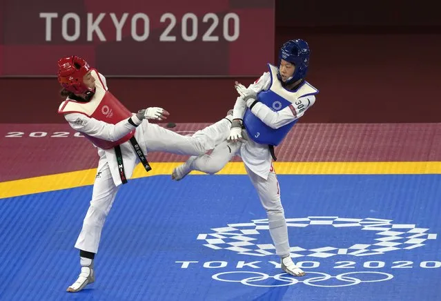 Kimia Alizadeh Zonoozi, Refugee Olympic Team, left, attacks China's Zhou Lijun during the taekwondo women's 57kg match at the 2020 Summer Olympics, Sunday, July 25, 2021, in Tokyo, Japan. (Photo by Themba Hadebe/AP Photo)