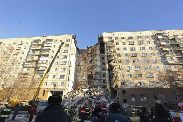 Emergency Situations employees working at the scene of a collapsed apartment building in Magnitogorsk, a city of 400,000 people, about 1,400 kilometers (870 miles) southeast of Moscow, Russia, Monday, December 31, 2018. Russian emergency officials say that at least four people have died after sections of the apartment building collapsed after an apparent gas explosion in the Ural Mountains region. (Photo by Maxim Shmakov/AP Photo)