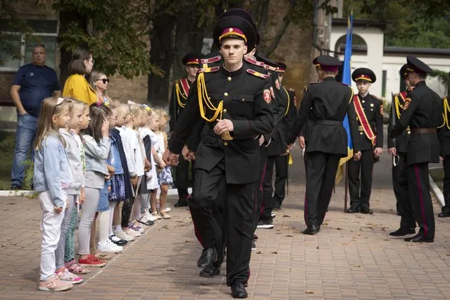 Young schoolgirls watch as cadets march during a rehearsal of a ceremony on the first day of school at a cadet lyceum in Kyiv, Ukraine, Thursday, September 1, 2022. (Photo by Efrem Lukatsky/AP Photo)