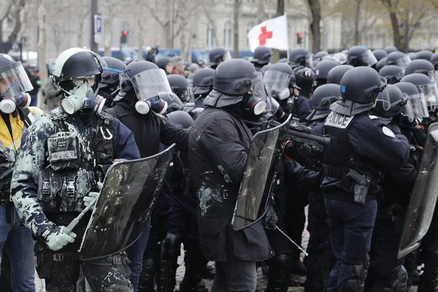 Riot police take position during clashes yellow vest protesters clash around the Arc of Triomphe in Paris, France, Saturday, January 12, 2019. Authorities deployed 80,000 security forces nationwide for a ninth straight weekend of anti-government protests. (Photo by Kamil Zihnioglu/AP Photo)