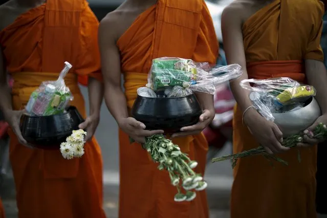 Buddhist monks wait to receive alms during Makha Bucha day near Wat Phrathat Doi Suthep in the northern capital of Chiang Mai, Thailand, February 22, 2016. Makha Bucha Day honours Buddha and his teachings, and falls on the full moon day of the third lunar month. (Photo by Athit Perawongmetha/Reuters)