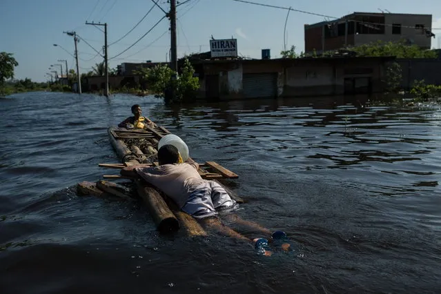 Brothers use a self made raft after buying food in Vila Velha, Espirito Santo state, Brazil, on December 28, 2013. (Photo by Yasuyoshi Chiba/AFP Photo)