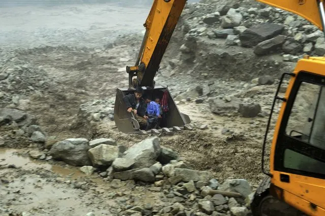 An excavator moves villagers away from a flooded area during heavy rainfall in Yingxiu, Wenchuan county, Sichuan province, July 10, 2013. (Photo by Reuters/Stringer)