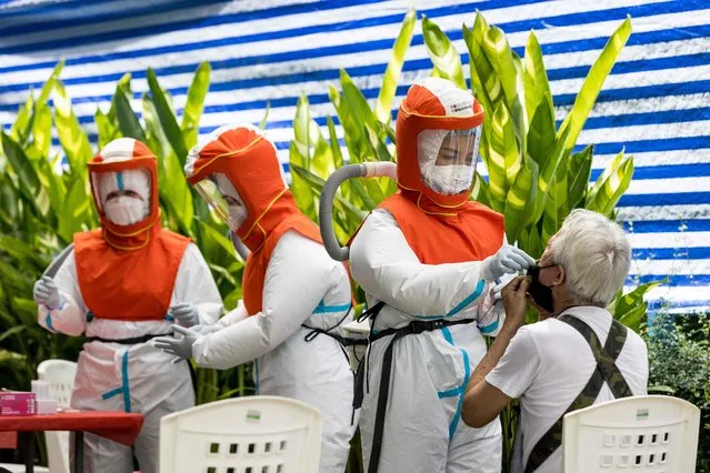 Health workers wearing personal protective equipment (PPE) administer a Covid-19 coronavirus nasal swab during a round of testing of workers outside a market in Bangkok on September 4, 2021. (Photo by Jack Taylor/AFP Photo)