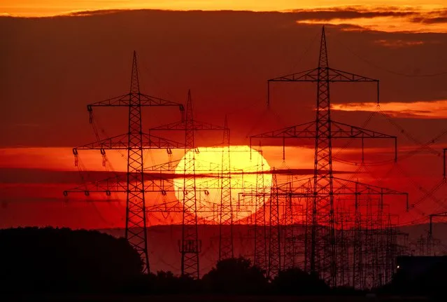 The sun rises behind power poles in the outskirts of Frankfurt, Germany, Saturday, July 1, 2023. (Photo by Michael Probst/AP Photo)