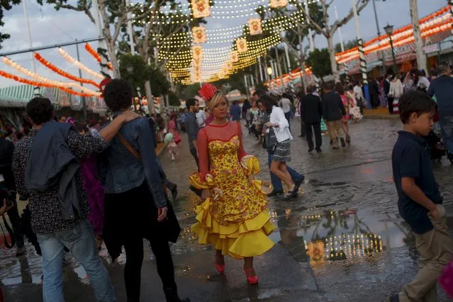 A woman wearing a sevillana dress walks during the traditional Feria de Abril (April fair) in the Andalusian capital of Seville, southern Spain, April 21, 2015. (Photo by Marcelo del Pozo/Reuters)
