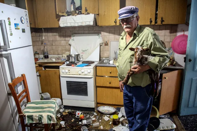 A man holds a coat inside a demolished house following an earthquake, in Saba village on Crete island, on September 27, 2021. A strong earthquake struck the Greek island of Crete early on September 27, 2021, killing a man who was working in a church that collapsed and injuring nine others, the civil protection agency said. (Photo by Costas Metaxakis/AFP Photo)