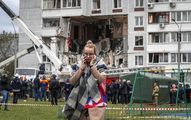 A woman walks as Rescue team members at work in the aftermath of a gas explosion at a nine-storey residential building in Noginsk, Moscow region, Russia, 08 September 2021. The explosion killed two people while nine others were hospitalized. (Photo by Yuri Kochetkov/EPA/EFE)