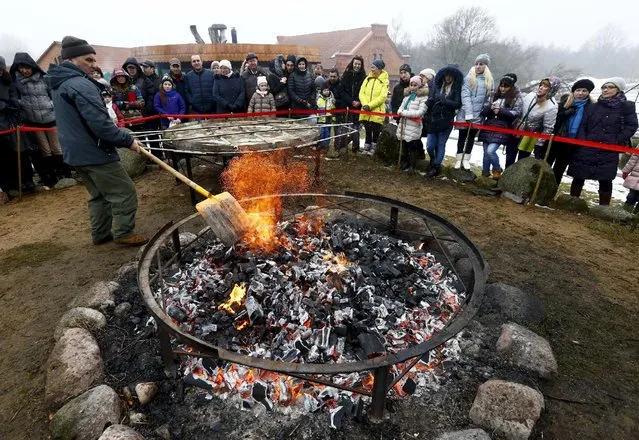 A man prepares the fire for frying dranik, a potato pancake that is the national dish of Belarus, in the Sula History Park near the village of Sula, Belarus March 7, 2016. (Photo by Vasily Fedosenko/Reuters)