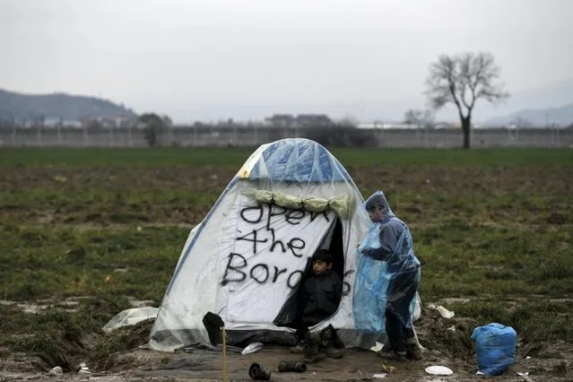 Two boys look from a tent scribbled with the words “Open the borders” at a makeshift camp for refugees and migrants at the Greek-Macedonian border, near the village of Idomeni, Greece March 16, 2016. (Photo by Alkis Konstantinidis/Reuters)