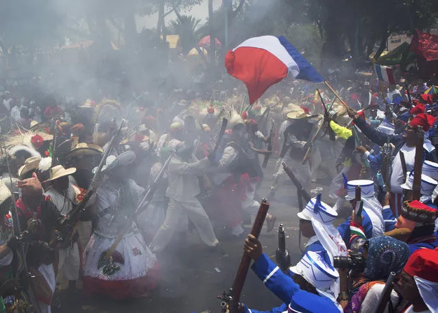 Local residents dressed as Zacapoaxtla Indians, left, and French soldiers, right, clash during a reenactment of the battle of Puebla during Cinco de Mayo celebrations in the Penon de los Banos neighborhood of Mexico City, Tuesday, May 5, 2015. (Photo by Rebecca Blackwell/AP Photo)