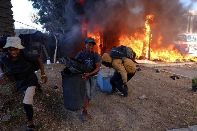 Occupants remove their belongings from their makeshift shelters after a fire broke out following their eviction from a piece of land, called “tent city”  which they unlawfully occupied near the Green Point tennis courts in Cape Town, South Africa, on February 22, 2024. (Photo by Esa Alexander/Reuters)