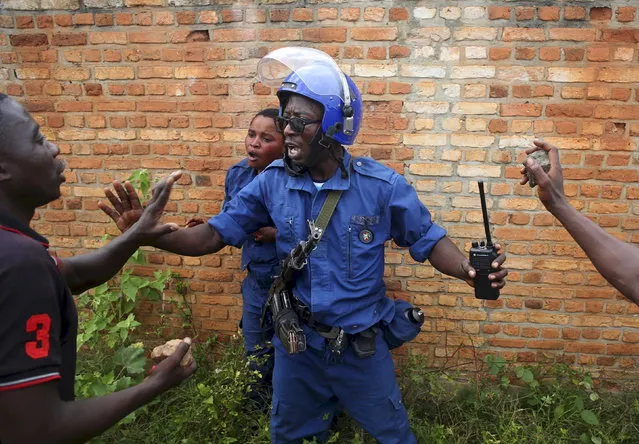 A policeman tries to protect a female police officer accused of shooting a protester in the Buterere neighborhood of Bujumbura, Burundi, May 12, 2015. (Photo by Goran Tomasevic/Reuters)