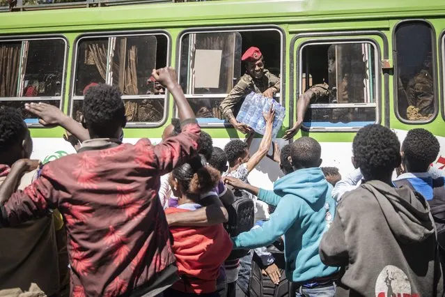 A soldier receives a pack of bottled water as residents react while a convoy of soldiers from the Ethiopian National Defence Forces drive through Sendafa on December 7, 2021. (Photo by Amanuel Sileshi/AFP Photo)