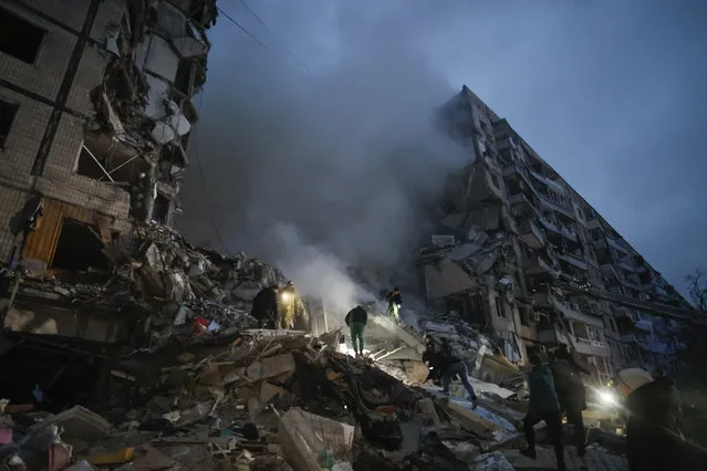 Local residents clear the rubble after a Russian rocket hit a multistory building leaving many people under debris in Dnipro, Ukraine, Saturday, January 14, 2023. (Photo by Roman Chop/AP Photo)