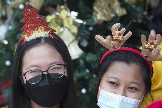 Women wearing masks to curb the spread of the coronavirus work on decorations to celebrate Christmas at a church in Bali, Indonesia on Friday, December 24, 2021. (Photo by Firdia Lisnawati/AP Photo)