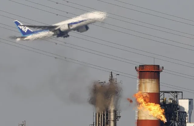 A plane flies over a chimney of an oil refinery in Kawasaki, south of Tokyo in this January 30, 2013 file photo. (Photo by Toru Hanai/Reuters)