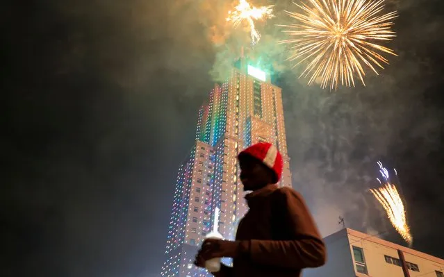 A reveller stands as fireworks explode over the UAP Old Mutual Tower during the New Year's Eve celebrations in Nairobi, Kenya on January 1, 2022. (Photo by Thomas Mukoya/Reuters)