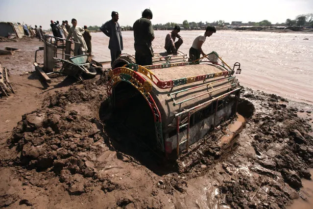 People try to pull a vehicle from mud nearby a flooded road following torrential rains on the outskirts of Peshawar, Pakistan, 05 April 2016. (Photo by Bilawal Arbab/EPA)