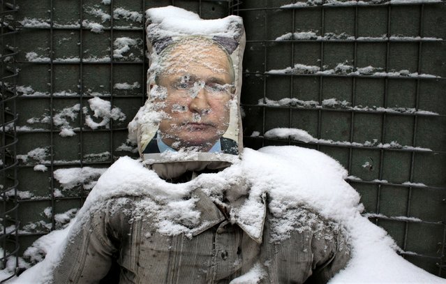 A poster of Russian President Vladimir Putin  is used as target practice along a trench on the frontline with Russia-backed separatists near Zolote village, in the Lugansk region, on January 21, 2022. Ukraine's Foreign Minister Dmytro Kuleba on January 22, 2022, slammed Germany for its refusal to supply weapons to Kyiv, urging Berlin to stop “undermining unity“ and “encouraging Vladimir Putin” amid fears of a Russian invasion. (Photo by Anatolii Stepanov/AFP Photo)