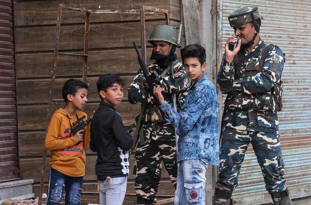 Children play with toy guns next to Indian security force personnel during restrictions after the scrapping of the special constitutional status for Kashmir by the government, in Srinagar, August 13, 2019. (Photo by Danish Ismail/Reuters)