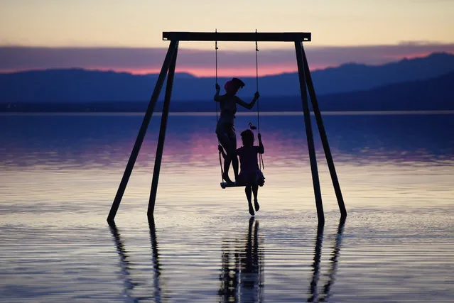 Attendees play on a swing installed in the Salton Sea on the first day of the Bombay Beach Biennale, March 22, 2019 in Bombay Beach, California. The tiny desert town, once a thriving resort along the Salton Sea, is among the poorest communities in California, but the remote hamlet is experiencing a rebirth of sorts as a group of artists and well-heeled sponsors have taken up residence, buying up dirt-cheap property and organizing an annual three-day festival called the Bombay Beach Biennale. (Photo by Robyn Beck/AFP Photo)