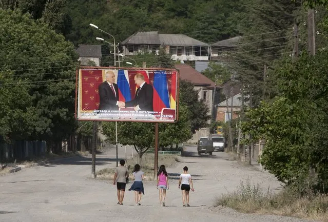 People walk near a billboard, showing President of the breakaway region of South Ossetia Leonid Tibilov during a meeting with Russian President Vladimir Putin, in Leningori (or Akhalgori), in the breakaway region of South Ossetia, Georgia, July 6, 2015. (Photo by Kazbek Basaev/Reuters)