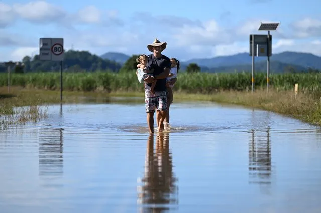 John Lawrence and Payton Campbell (unseen at rear) with their children Harlow and Aria inspect a flooded road near their home on March 02, 2022 in Dungay, Northern NSW, Australia. Several northern New South Wales towns have been forced to evacuate as Australia faces unprecedented storms and the worst flooding in a decade. (Photo by Dan Peled/Getty Images)