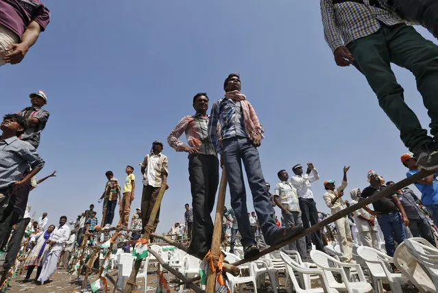 Supporters of India's ruling Congress party, stand on poles to get a glimpse of Rahul Gandhi (not pictured), Congress party's vice president and son of Congress chief Sonia Gandhi, during an election campaign rally in the western Indian state of Gujarat April 26, 2014. (Photo by Reuters/Amit)