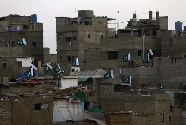 Pakistan's national flags are seen on the nearby residential buildings during the first party rally of Pak Sarzameen Party (PSP) political party in Karachi, Pakistan, April 24, 2016. (Photo by Akhtar Soomro/Reuters)