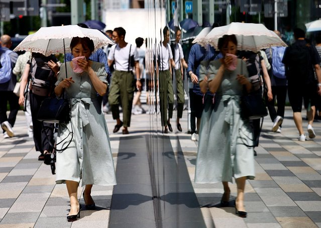 A passerby holding a parasol wipes her face as she walks on the street as the Japanese government issued a heatstroke alert in Tokyo and other prefectures, in Tokyo, Japan on July 9, 2024. (Photo by Issei Kato/Reuters)