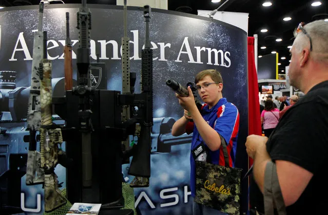 Blaine Bushnell (13) and his father Justin look over Alexander Arms guns at the National Rifle Association's annual meetings & exhibits show in Louisville, Kentucky, May 21, 2016. (Photo by John Sommers II/Reuters)