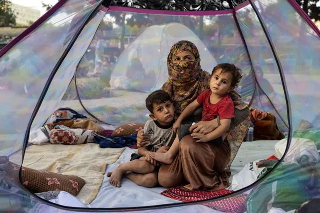 Farzia, 28, who lost her husband in Baghlan one week ago to fighting by the Taliban sits with her children, Subhan, 5, and Ismael ,2, in a tent at a makeshift IDP camp in Share-e-Naw park to various mosques and schools on August 12, 2021 in Kabul, Afghanistan. People displaced by the Taliban advancing are flooding into the Kabul capital to escape the Taliban takeover of their provinces. (Photo by Paula Bronstein/Getty Images)