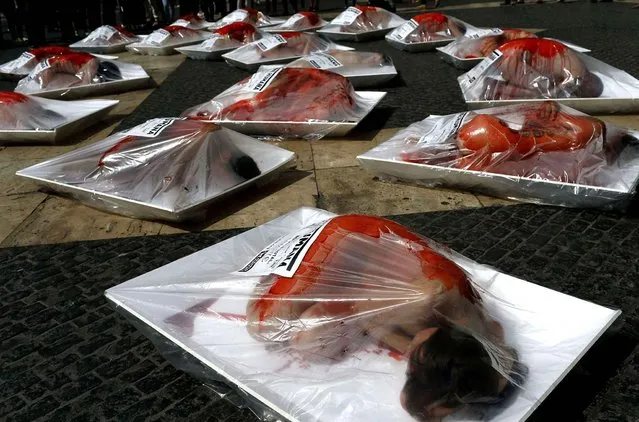 Activists from the Anima Naturalis animal rights group participate in a street performance, wrapped in simulated meat packaging trays in Barcelona, Spain, Sunday, May 22, 2016. The protest is to encourage people not to eat meat, raising the awareness of cruelty to farm animals and the health benefits of living without meat. The label on the package reads in Spanish; “Human Meat”. (Photo by Manu Fernandez/AP Photo)