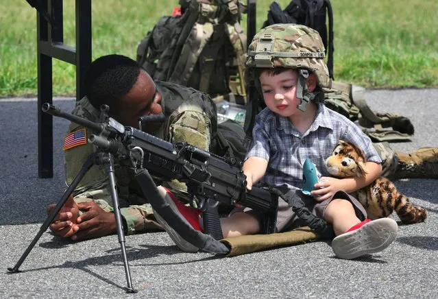 A US soldier looks at a boy posing with a M249 light machine gun during a ceremony to commemorate the 75th anniversary of the Eighth US Army at Camp Humphreys in Pyeongtaek on June 8, 2019. (Photo by Jung Yeon-je/AFP Photo)