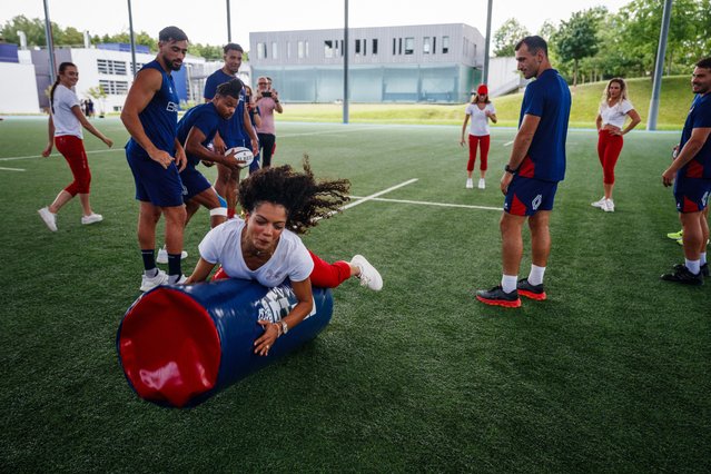 France's Antoine Dupont (R) and Paulin Riva (2R) look at a Moulin Rouge's dancer tackling as France national rugby sevens' players teach how to play rugby to Moulin Rouge's dancers at the National Rugby Centre in Marcoussis, near Paris, on July 17, 2024, ahead of the Paris 2024 Olympic and Paralympic Games. (Phoot by Dimitar Dilkoff/AFP Photo)