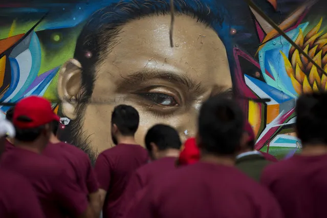 Party militants working at a campaign rally for Delfina Gomez, Mexico State gubernatorial candidate for the National Regeneration Movement, or MORENA, walk in front of street art in Nezahualcoyotl, Mexico state, Sunday, May 28, 2017. MORENA is attempting to unseat the ruling Institutional Revolutionary Party, known as the PRI, in Mexico state's June 4 gubernatorial elections. (Photo by Rebecca Blackwell/AP Photo)