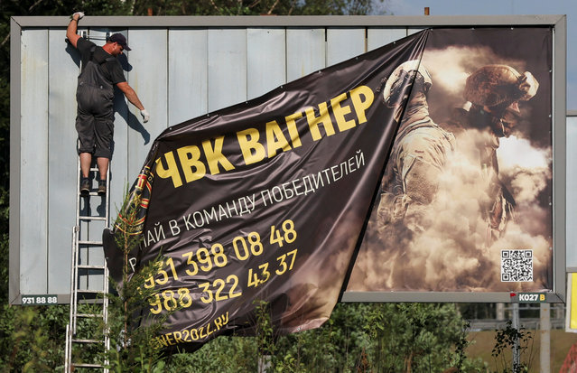 A worker removes an advertising banner promoting service in Wagner private mercenary group on the outskirts of Saint Petersburg, Russia, June 24, 2023. A slogan on the banner reads: “Accede to the team of victors!”. (Photo by Anton Vaganov/Reuters)