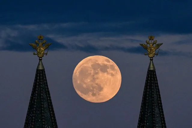 The full moon also known as Flower blood moon is pictured behind the two-headed eagle, the national symbol of Russia atop a building on Red Square in downtown Moscow on May 15, 2022. (Photo by Kirill Kudryavtsev/AFP Photo)