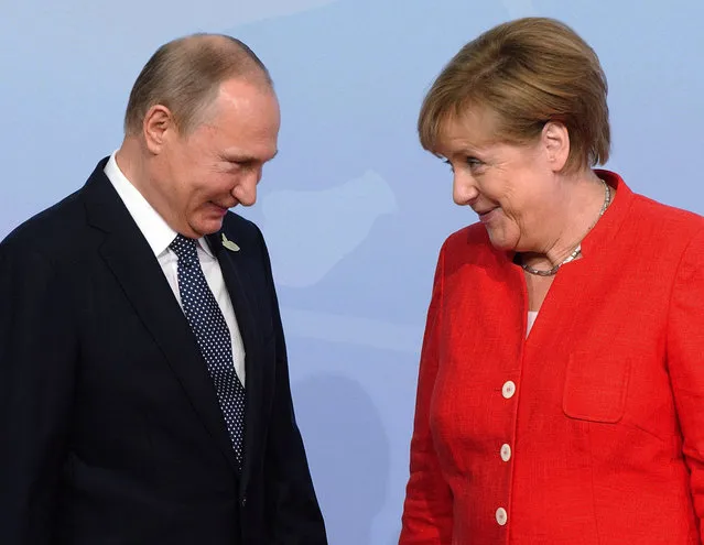 Russian President Vladimir Putin is greeted by German Chancellor Angela Merkel at the official welcoming ceremony at the G20 summit Friday, July 7, 2017 in Hamburg, Germany. (Photo by Ryan Remiorz/The Canadian Press via AP Photo)